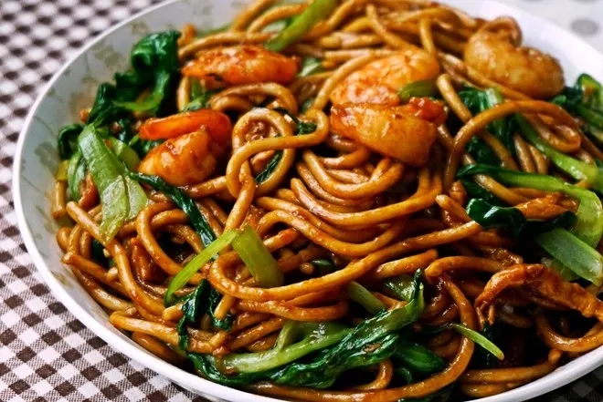 Golden brown stir-fried noodles with succulent shrimps, tender meat, and fresh vegetables in savory sauce